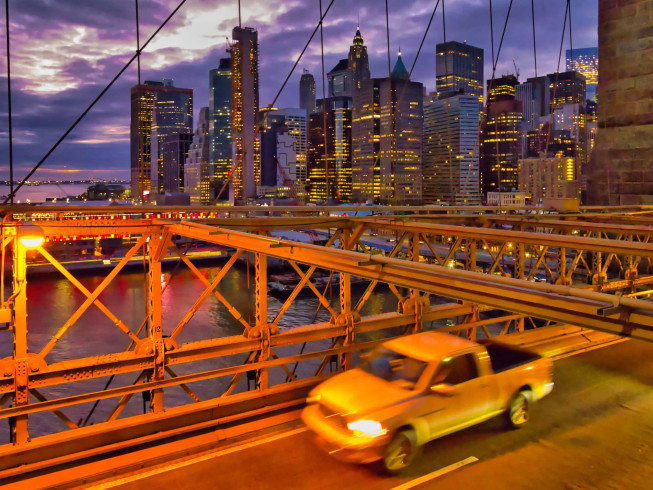 Yellow Chevrolet truck driving across Brooklyn Bridge at dusk, Christmas Day 2018